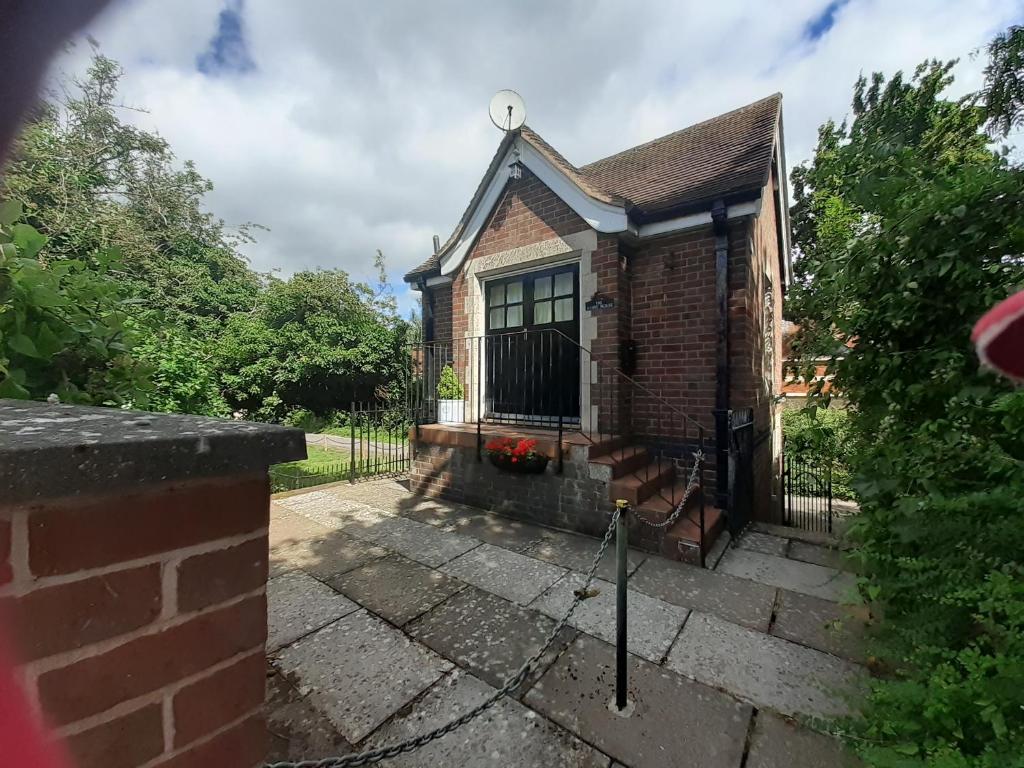 a small brick house with a black fence at Alum House in Tewkesbury