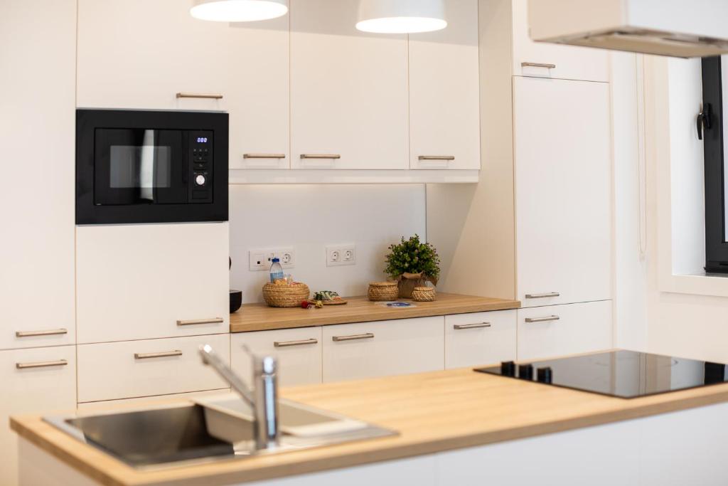 a white kitchen with a sink and a microwave at MyTrip Porto in Matosinhos