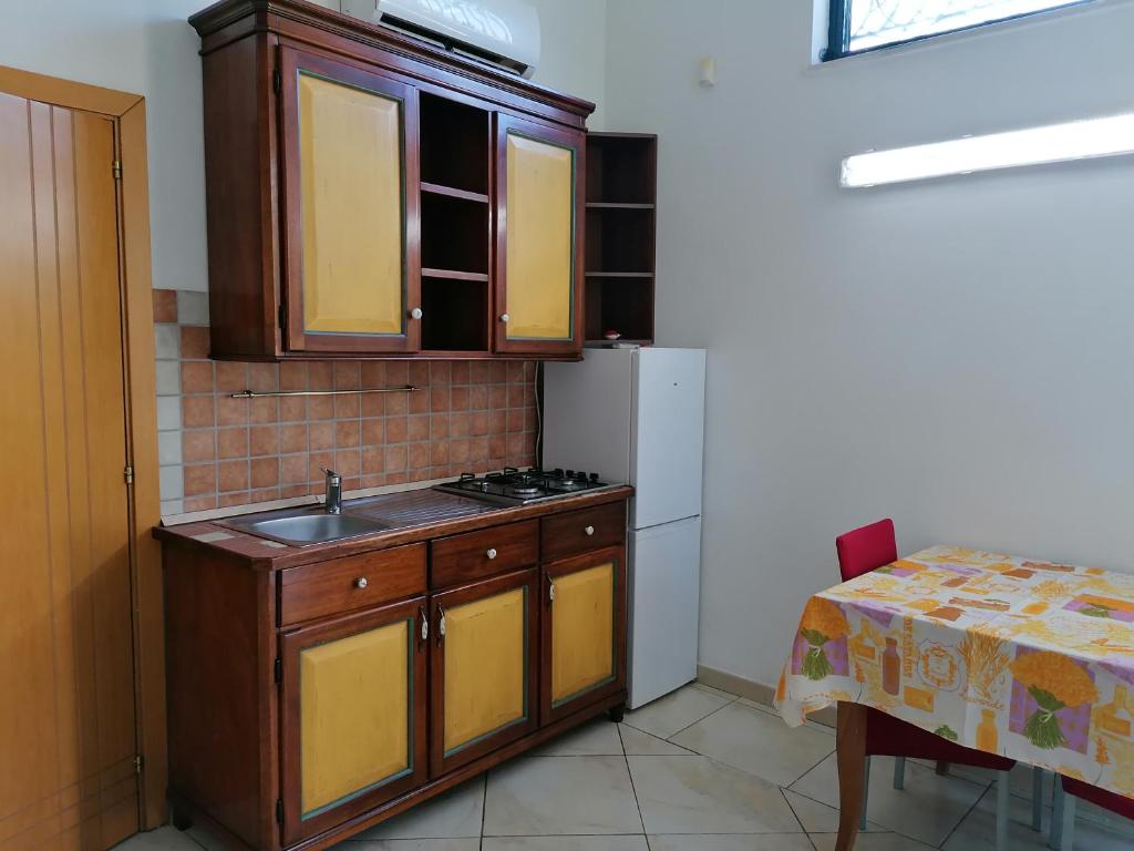 La cuisine est équipée d'un évier, d'un réfrigérateur et d'une table. dans l'établissement Casa fatone, à Cerignola