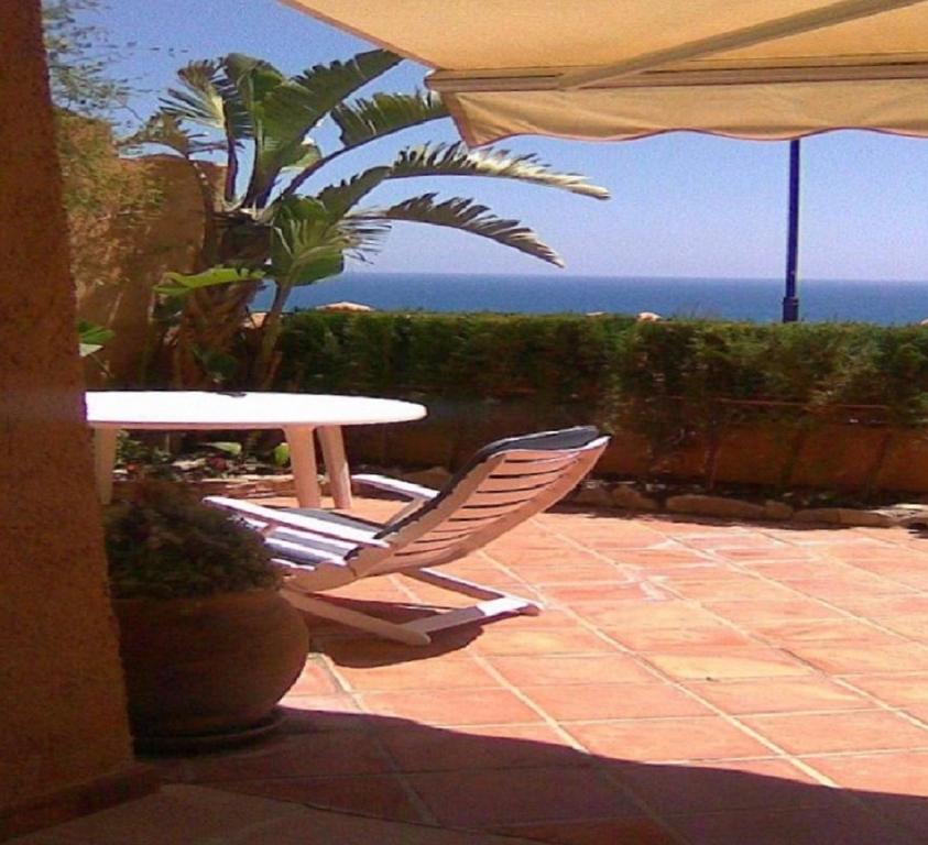 un patio con mesa, sillas y el océano en Apartamento Mascarat vistas al mar, en Altea