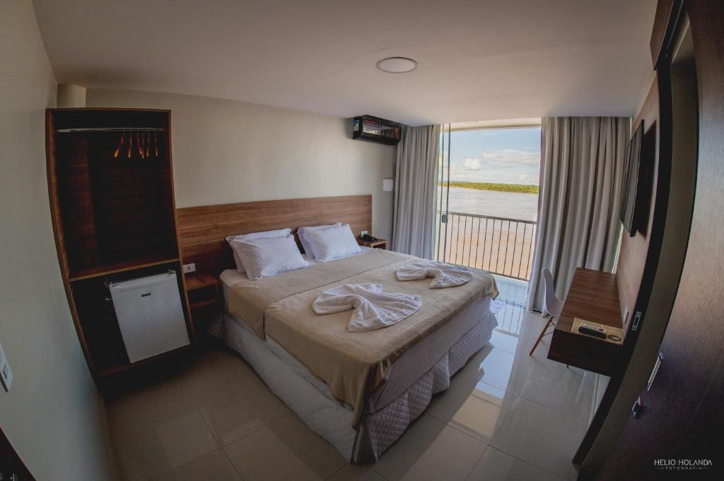 a hotel room with a bed and a large window at Hotel Orla do Rio Branco in Boa Vista