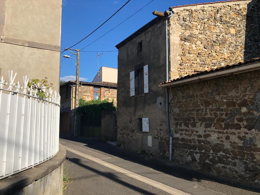 um beco com um edifício de tijolos e uma cerca branca em La Maisonnette auvergnate em Vertaizon