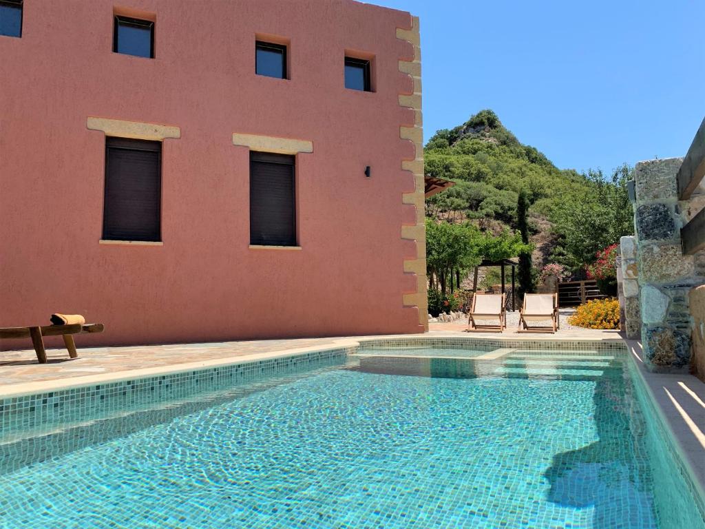 una piscina frente a una casa con un edificio en Archon Villa, en Pandeleḯmon