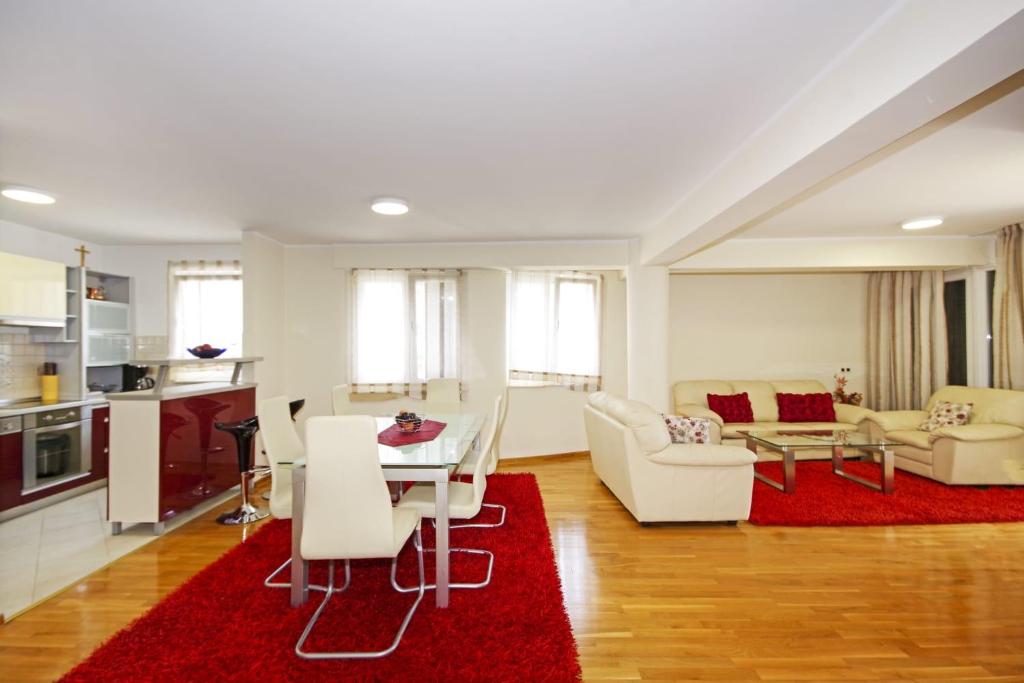 sala de estar con muebles blancos y alfombra roja en Delux Apartman Jukic, en Makarska