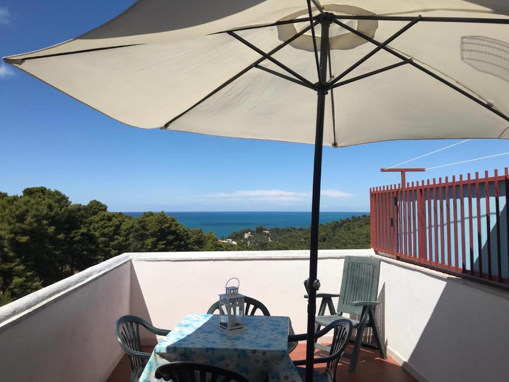 a table and chairs on a balcony with an umbrella at Villa Pineta in San Menaio