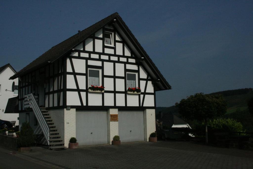 a black and white house with two white garage at Ferienhaus Zur Ennest in Schmallenberg