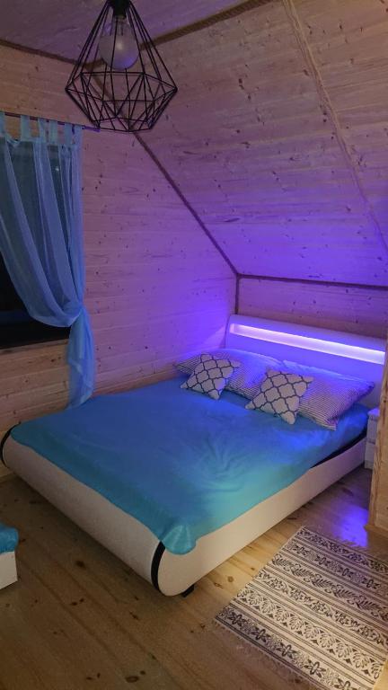 克羅科瓦的住宿－Domki Magnolia，紫色灯光客房内的一张床位