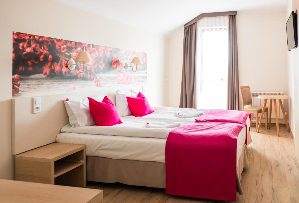 a bedroom with a large bed with pink pillows at Cicha Zdrój in Solec-Zdrój