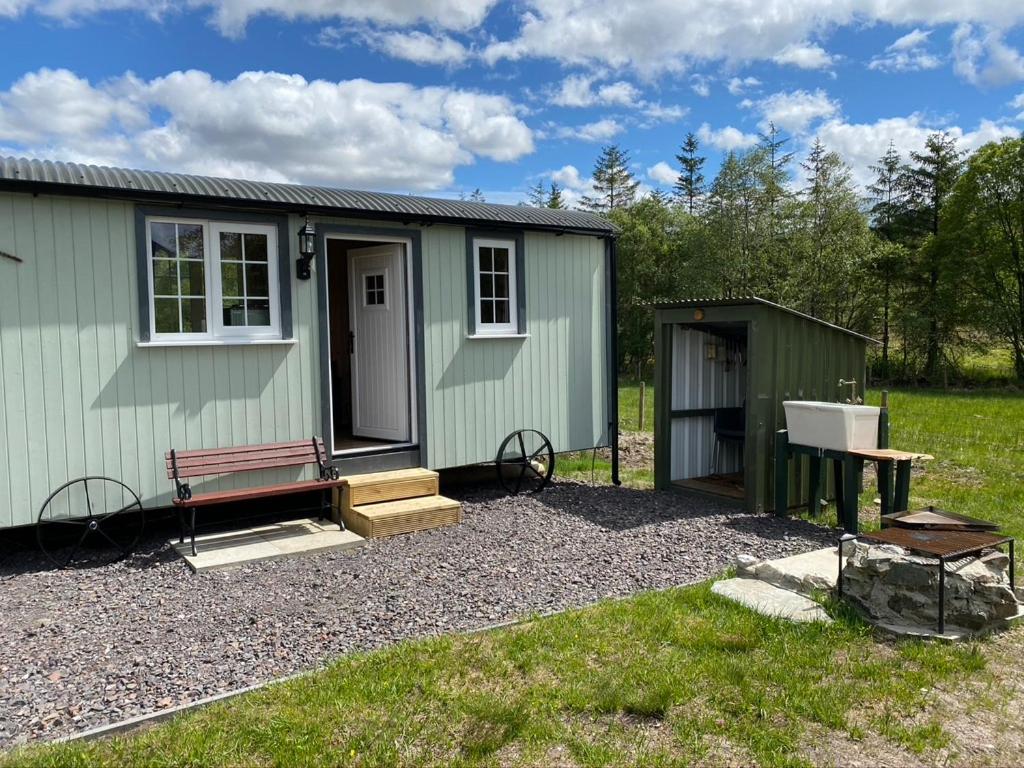 a green tiny house with a bench and a table at Wee Highland Hideaway Hut in Dalmally