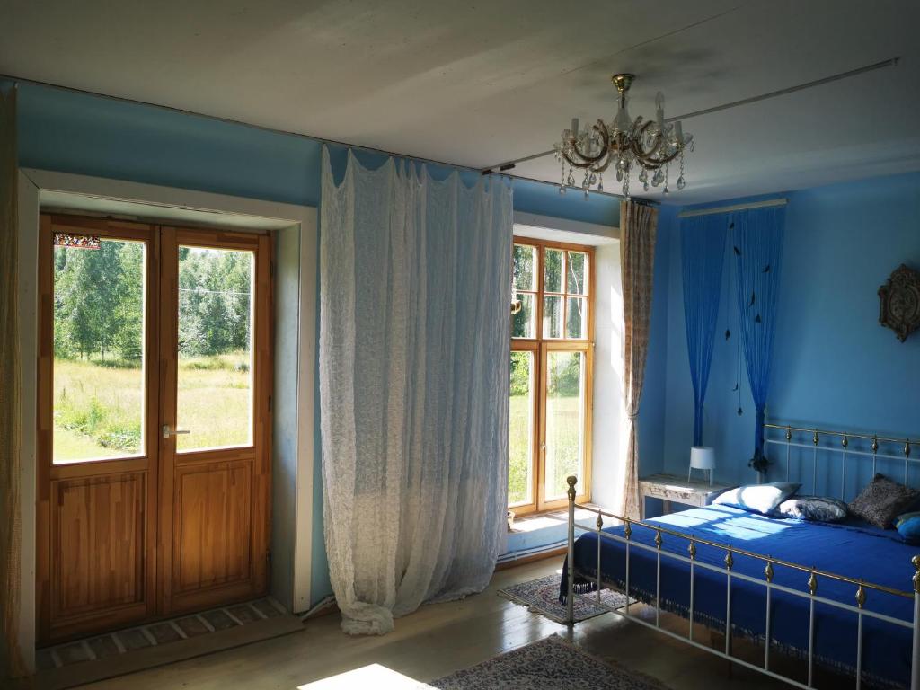 a bedroom with blue walls and a bed and a window at Gold Sun Zelta Saule in Matkule