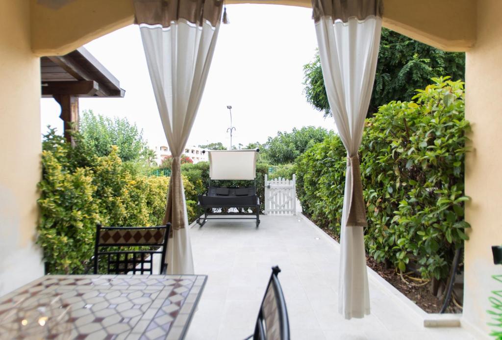 une terrasse avec des rideaux, une table et des chaises dans l'établissement Incantevole Villetta mare indipendente, à Marina di Pisticci