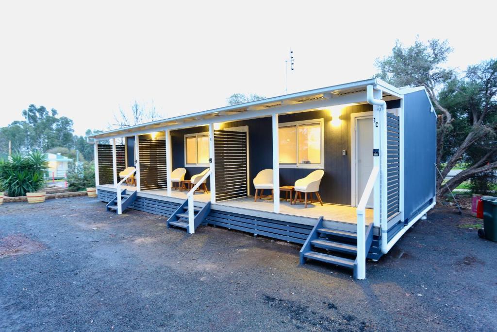 ein blaues modulares Haus mit Stühlen und einem Tisch in der Unterkunft Junee Tourist Park in Junee