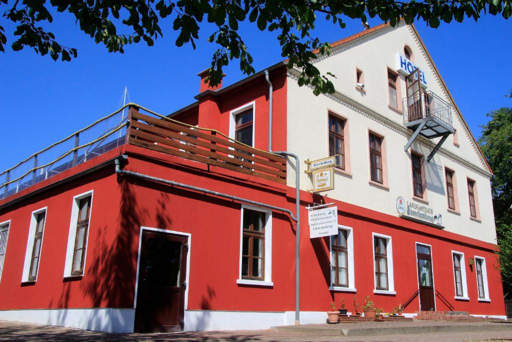 ein rot-weißes Gebäude an der Ecke einer Straße in der Unterkunft Landhotel Storchenkrug in Rühstädt