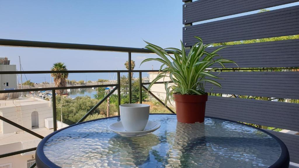 uma mesa com uma chávena de café e uma planta na varanda em Vista Marina em Kalamata