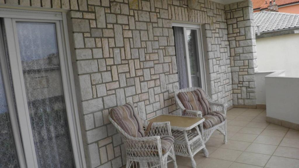 a patio with wicker chairs and a table on a building at Apartmani s dvije spavaće sobe 4 osobe in Selce