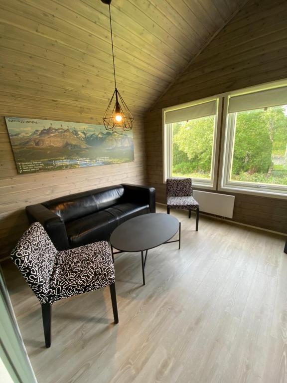 a living room with a couch and a table and chairs at Saltstraumen Hotels Hytter in Knapplund