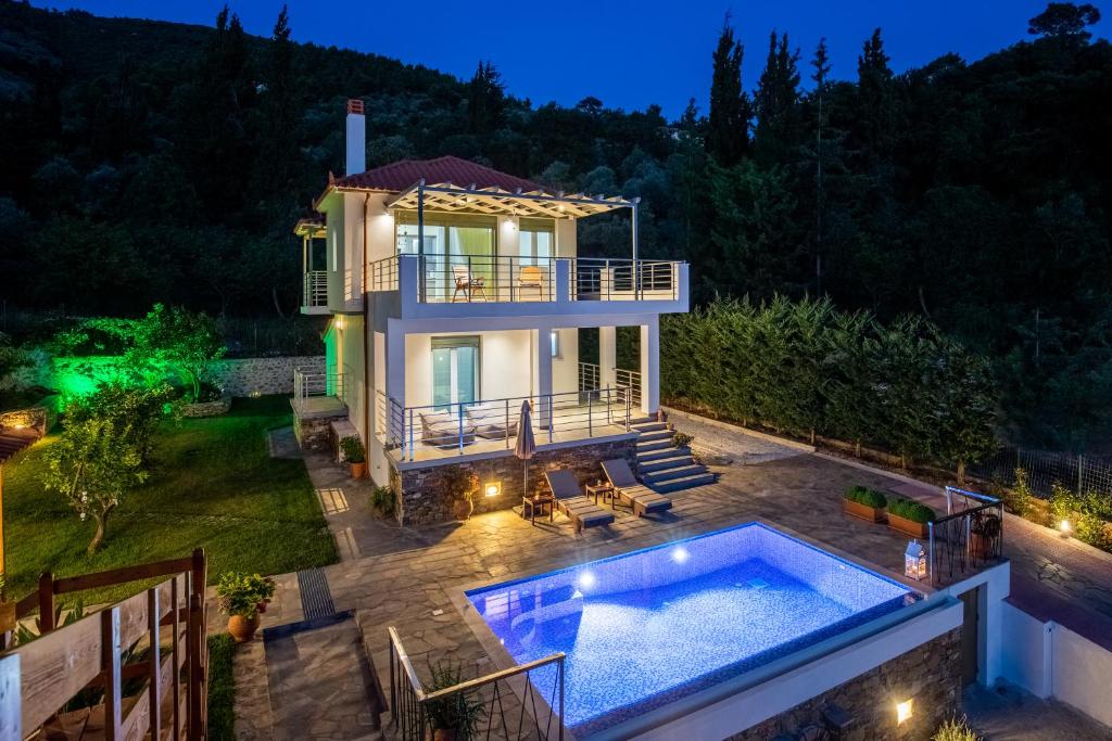 スコペロスにあるVilla Kotronakiの裏庭の夜間スイミングプール付きの家