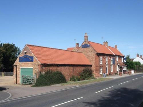 a brick building with an orange roof next to a street at The Lord Nelson Inn in Newark upon Trent