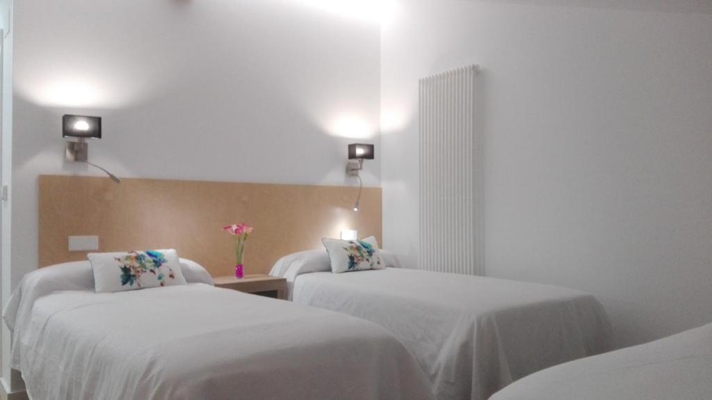 Habitación de hotel con 2 camas con sábanas blancas en Apartamentos Turísticos Los Picos, en Liérganes