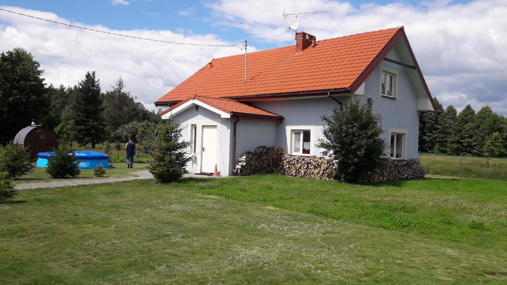 een wit huis met een oranje dak bij Sielska Chata in Fabianki