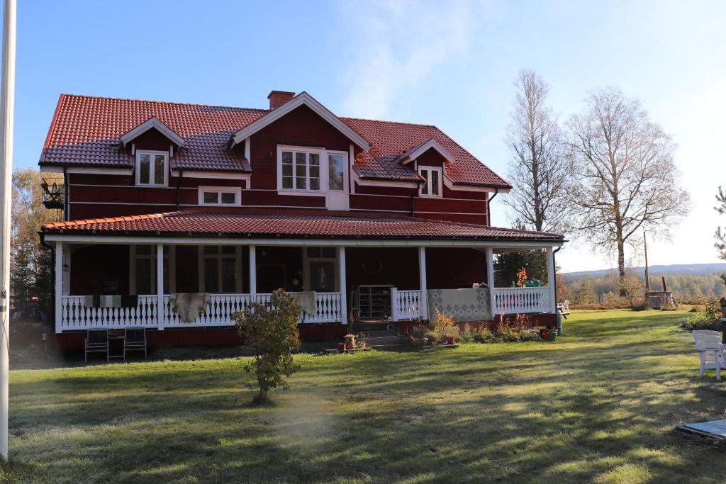 Casa roja grande con porche blanco en Anneberg Guesthouse, en Ekshärad