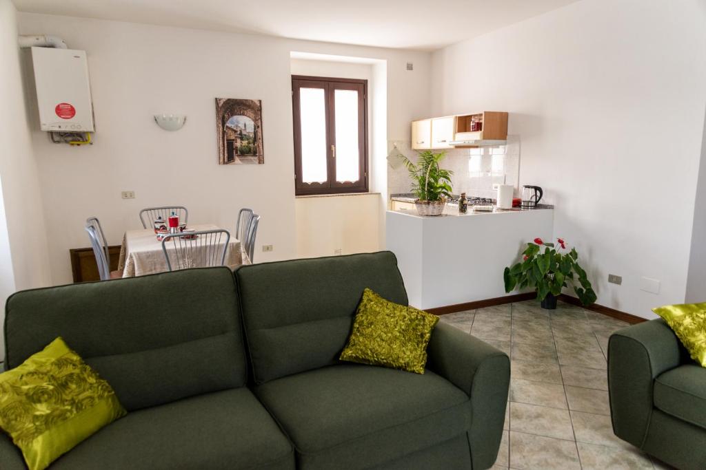 a living room with a green couch and a kitchen at Sulle orme di Francesco appartamento verde in Bastia Umbra
