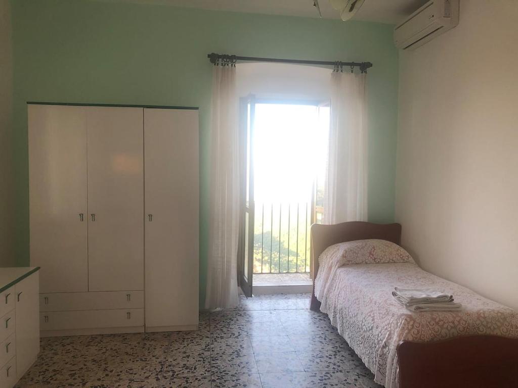 a bedroom with a bed and a large window at Case Vacanze Tra Mare e Monti "Da Nora" in Crucoli