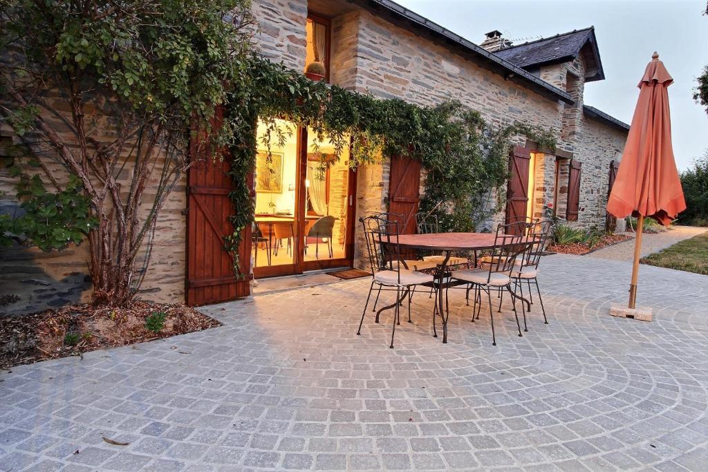 un patio con mesa, sillas y sombrilla en La Longère de La Chevallerais en La Chevallerais