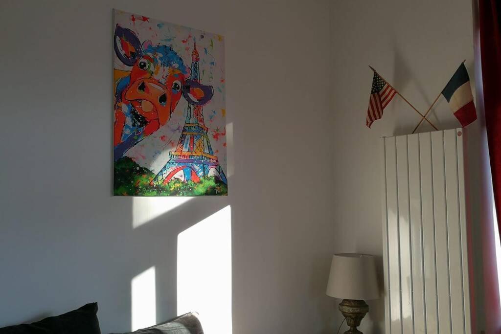 a painting of the eiffel tower is hanging on a wall at Les écuries du chateau in Commes