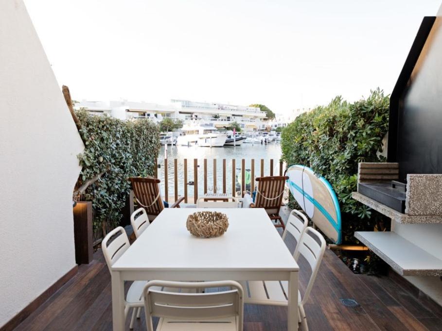 une table et des chaises blanches sur un balcon avec une rivière dans l'établissement Marina NS Guesthouse, au Grau-du-Roi