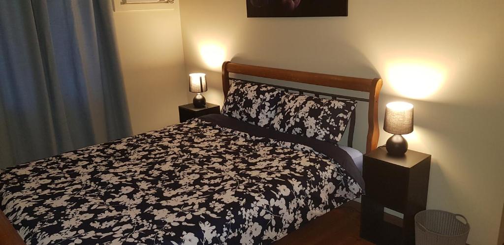 a bedroom with a black and white bed with two lamps at Warmont Apartments Self Contained Home in Whyalla