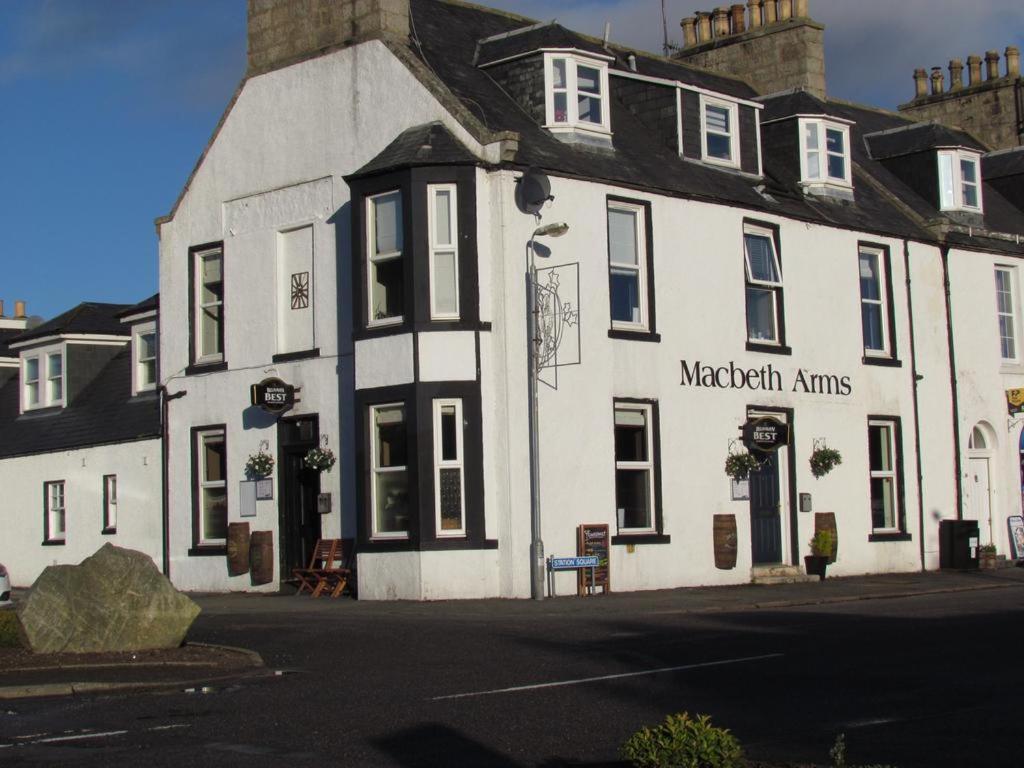 a white building with a sign on it at Macbeth Arms in Lumphanan
