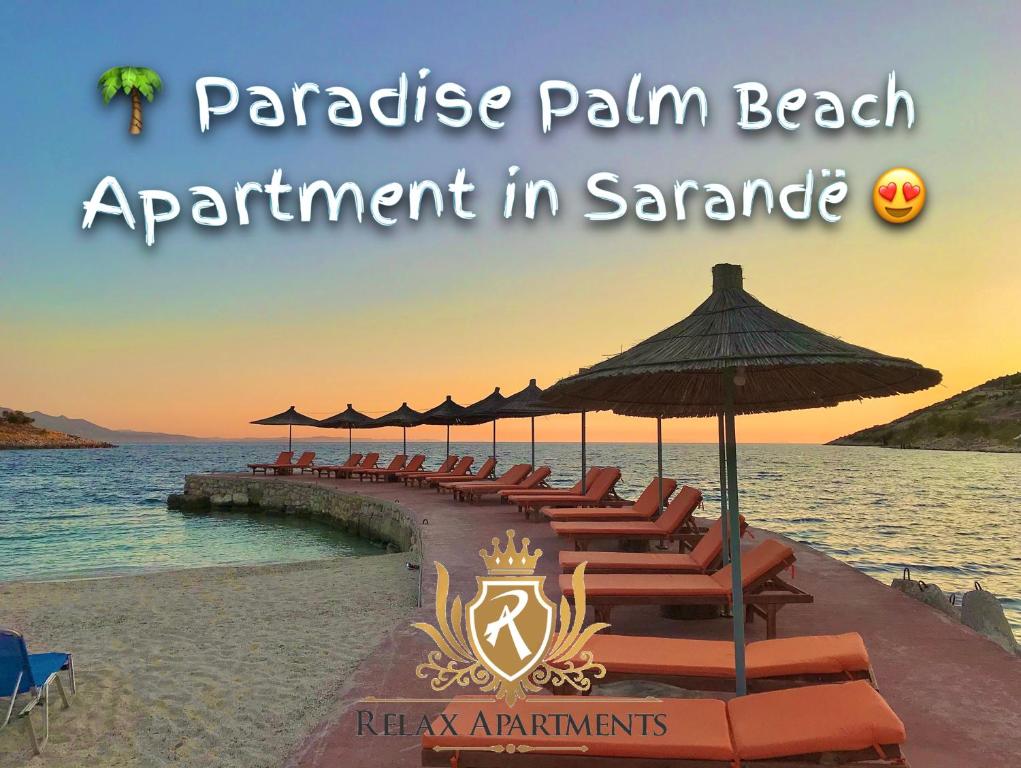 einen Strand mit Liegestühlen und Sonnenschirmen und dem Meer in der Unterkunft Paradise Palm Beach Apartment in Sarande in Sarandë