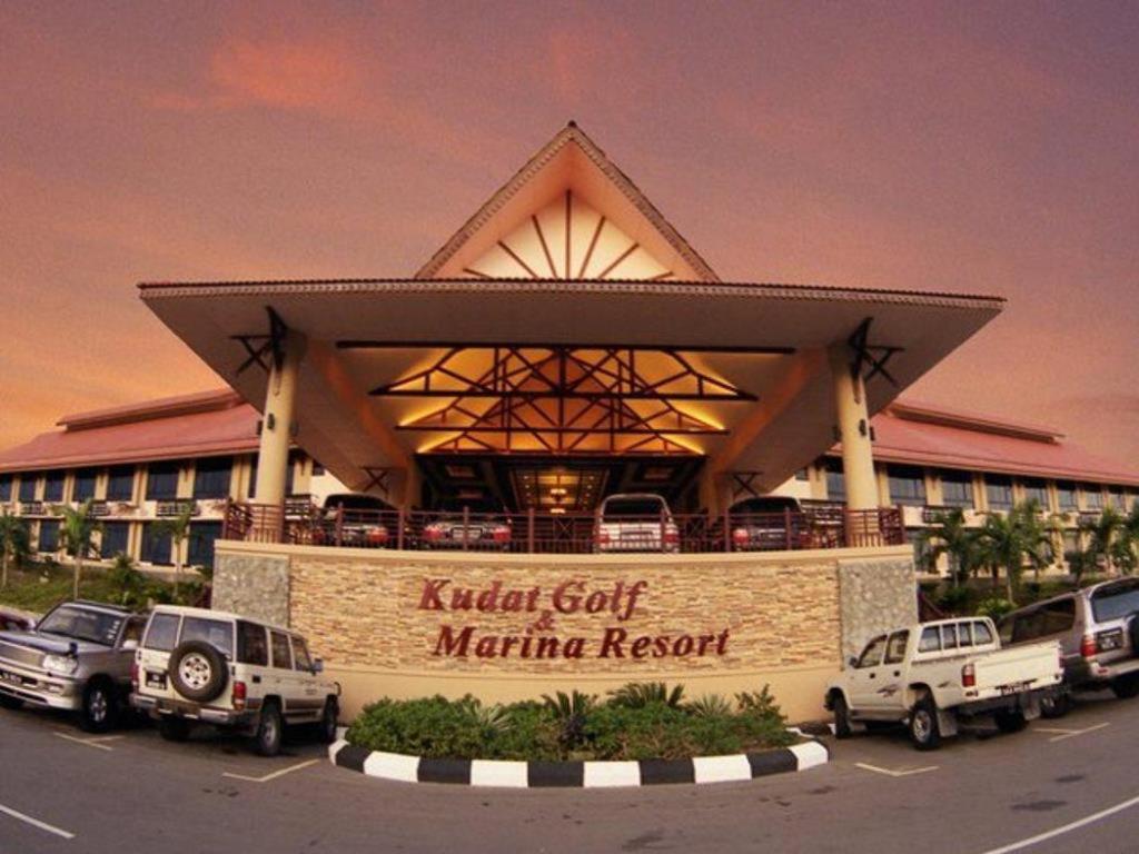 a hotel with cars parked in front of a building at Kudat Golf & Marina Resort in Kudat