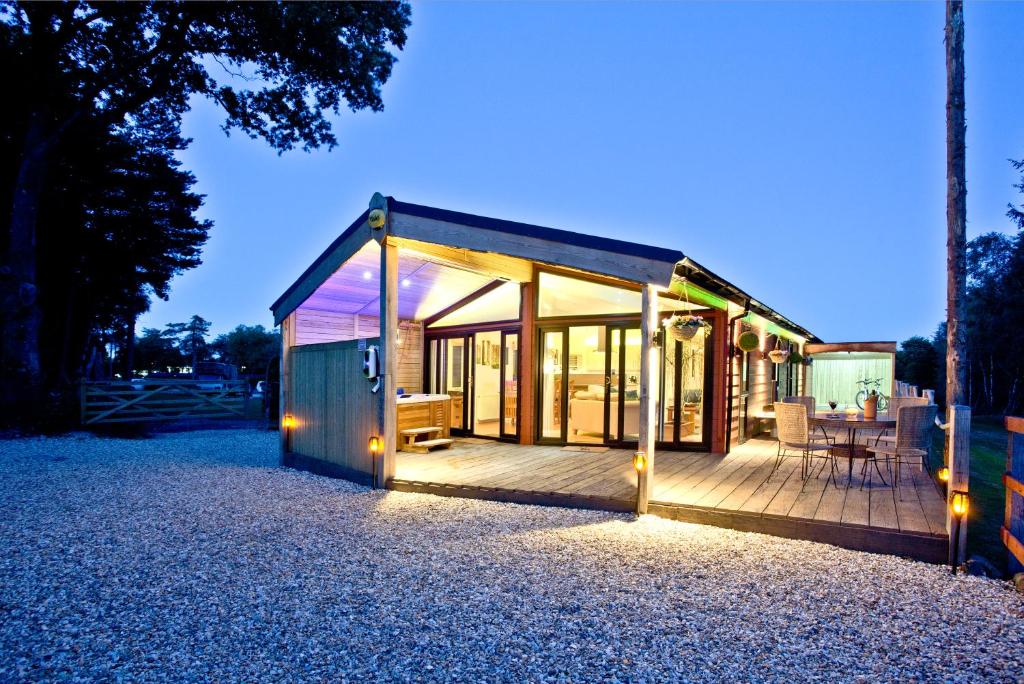 ein kleines Haus mit einer Terrasse mit Beleuchtung in der Unterkunft Haldon Forest Lodge, Exeter in Exeter