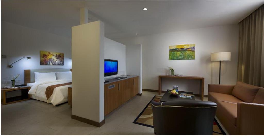 a hotel room with a bed and a television at Gloria Swiss Hotel & Apartment Sandakan in Sandakan