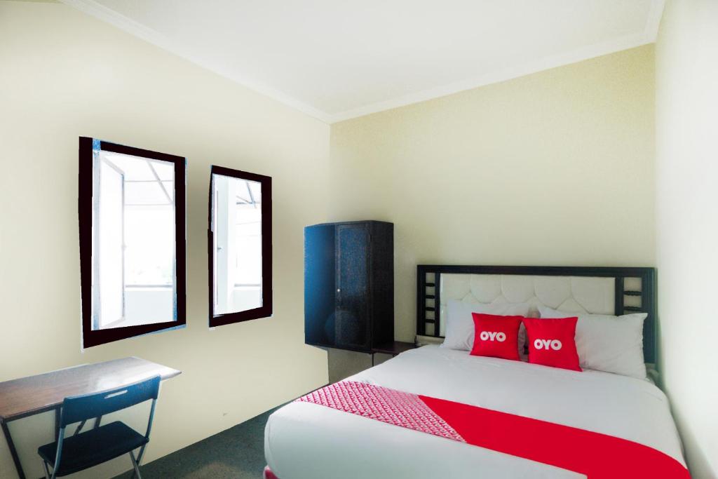 een slaapkamer met een bed met rode kussens en een bureau bij Super OYO 3354 Homia Residence in Mencil