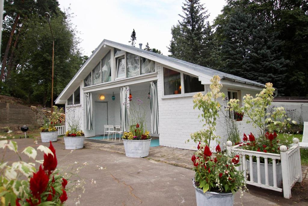 a small white house with potted plants in front of it at Smiling house & Baltic beach in Jūrmala