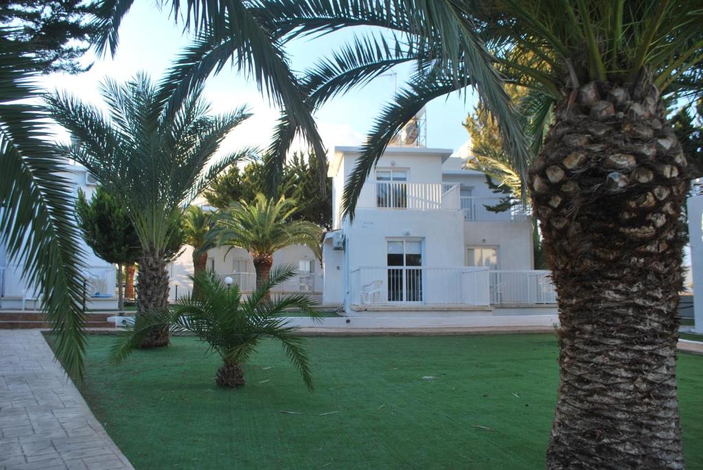 un edificio blanco con palmeras delante en Flisvos Beach Apartments en Protaras