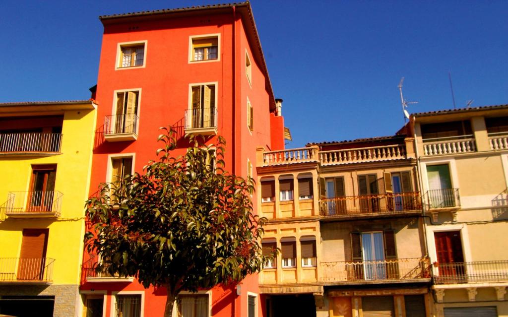 a tall orange building with a tree in front of it at Fonda Can Fasersia in Pobla de Segur