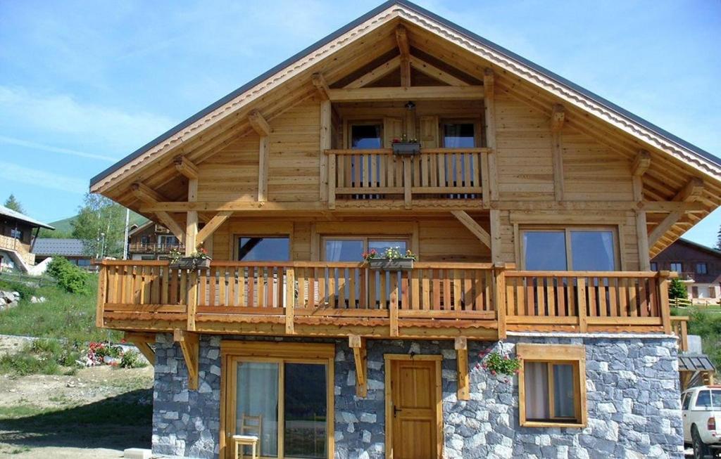 uma grande casa de madeira com uma varanda no topo em REFLET DES AIGUILLES - Chalet avec Jacuzzi em La Toussuire