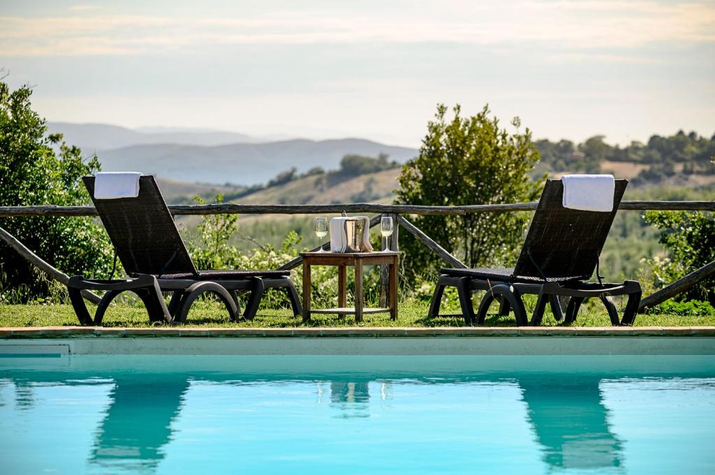 two chairs and a table next to a swimming pool at Azienda Agrituristica Le Chiuse in Manciano