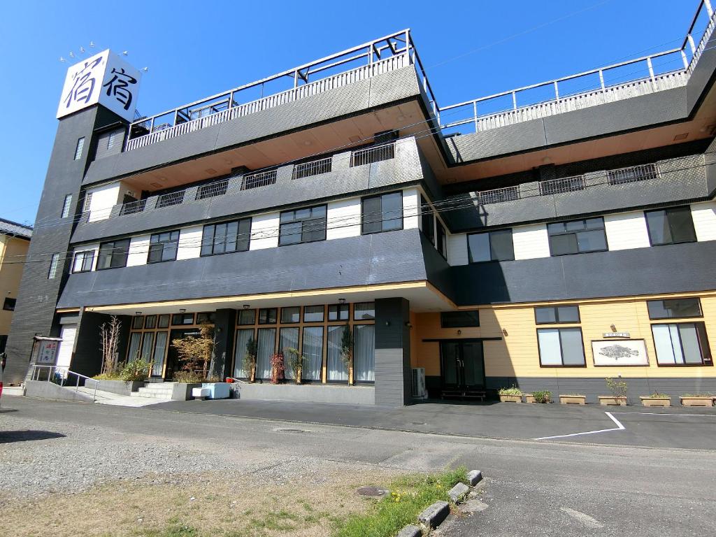 un edificio alto con balcón en la parte superior en Yurakuan Miyazaki en Miyazaki