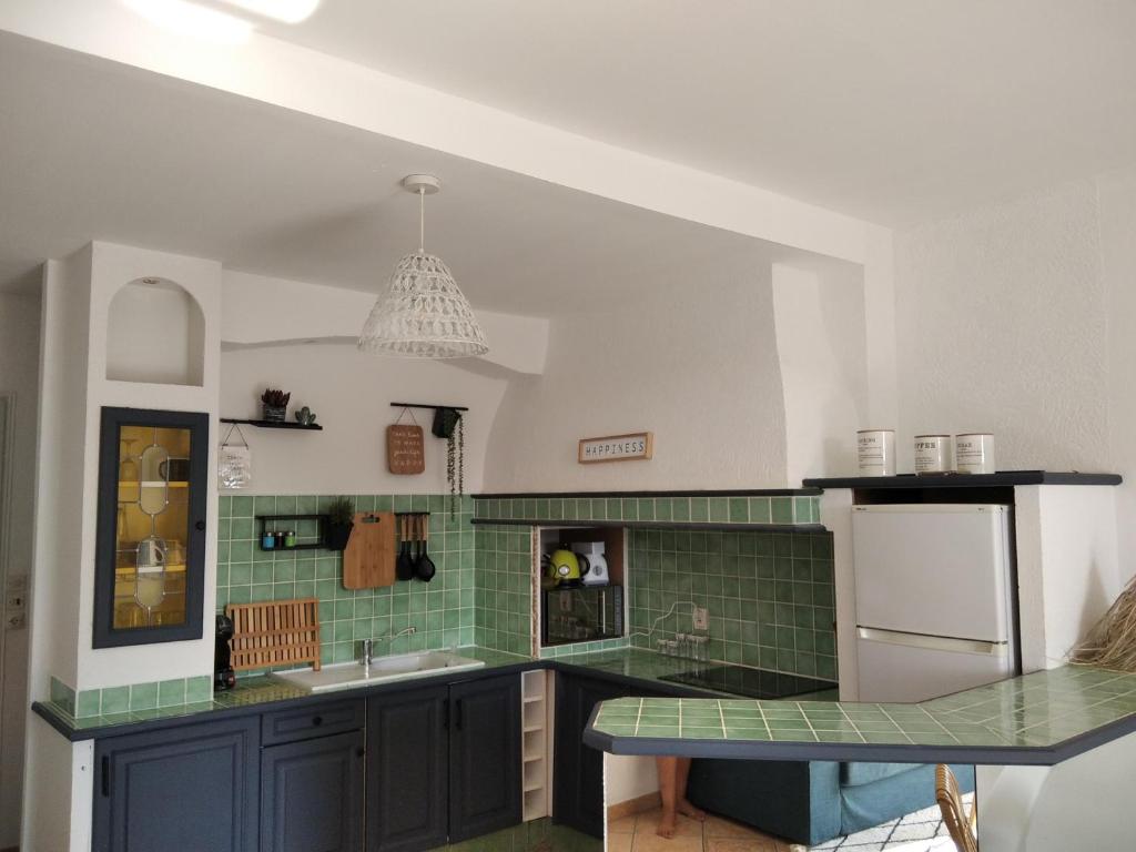 a kitchen with green and white tiles and a sink at Grand T2 au COEUR DE VILLE avec VUE SUR QUAIS ET MER in Sète
