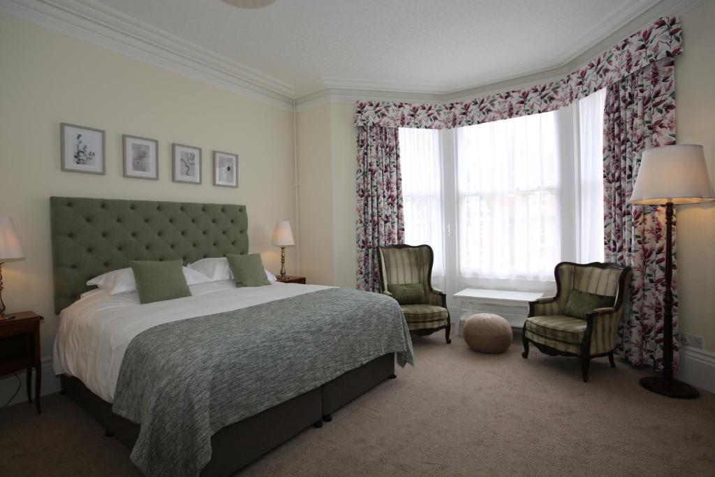 a bedroom with a bed and two chairs and a window at The Cordelia in Scarborough