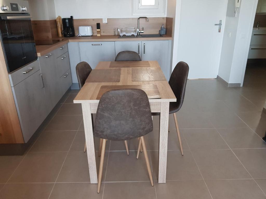 uma cozinha com uma mesa de madeira e cadeiras em Les marines Agay em Agay - Saint-Raphaël