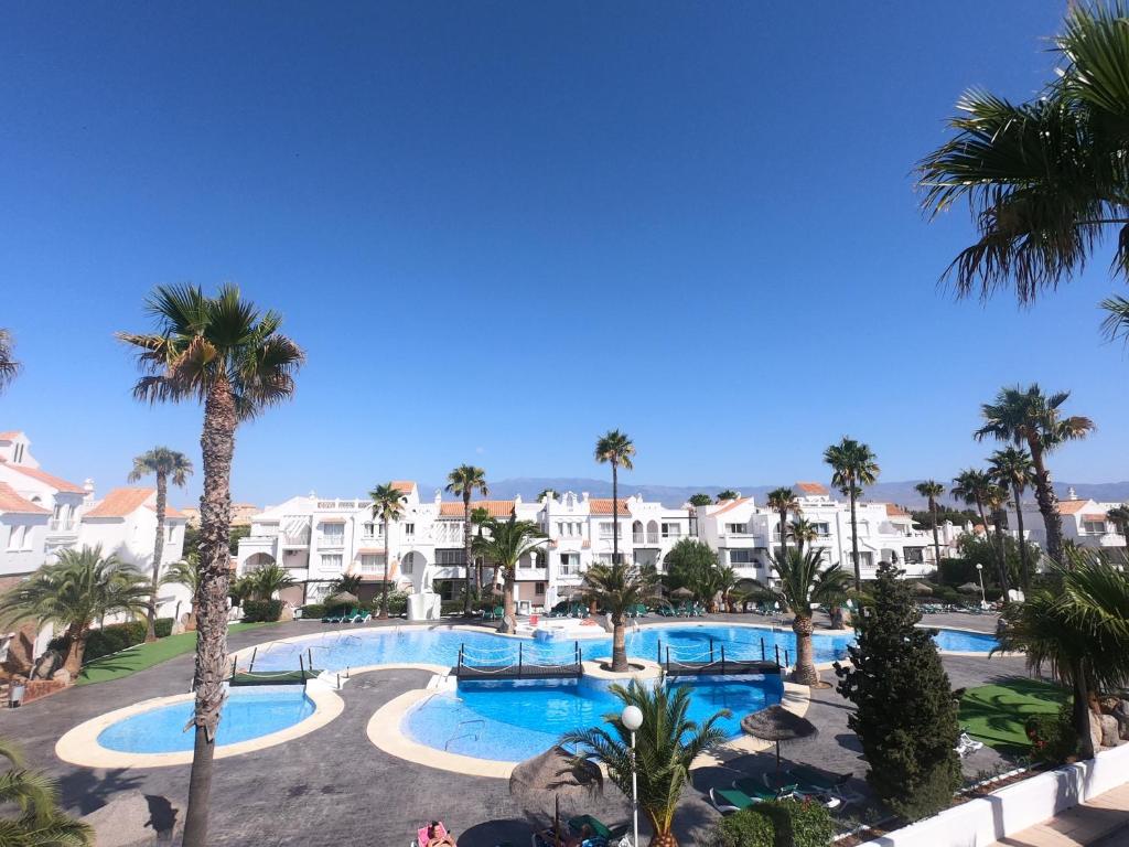 vistas a una piscina del complejo con palmeras y edificios en Apartamentos Golf Center, en Roquetas de Mar