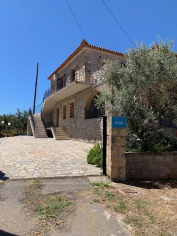 una gran casa de ladrillo con un cartel azul delante de ella en ΤΟ ΠΕΤΡΙΝΟ / THE PETRINO APARTMENTS, en Stoupa