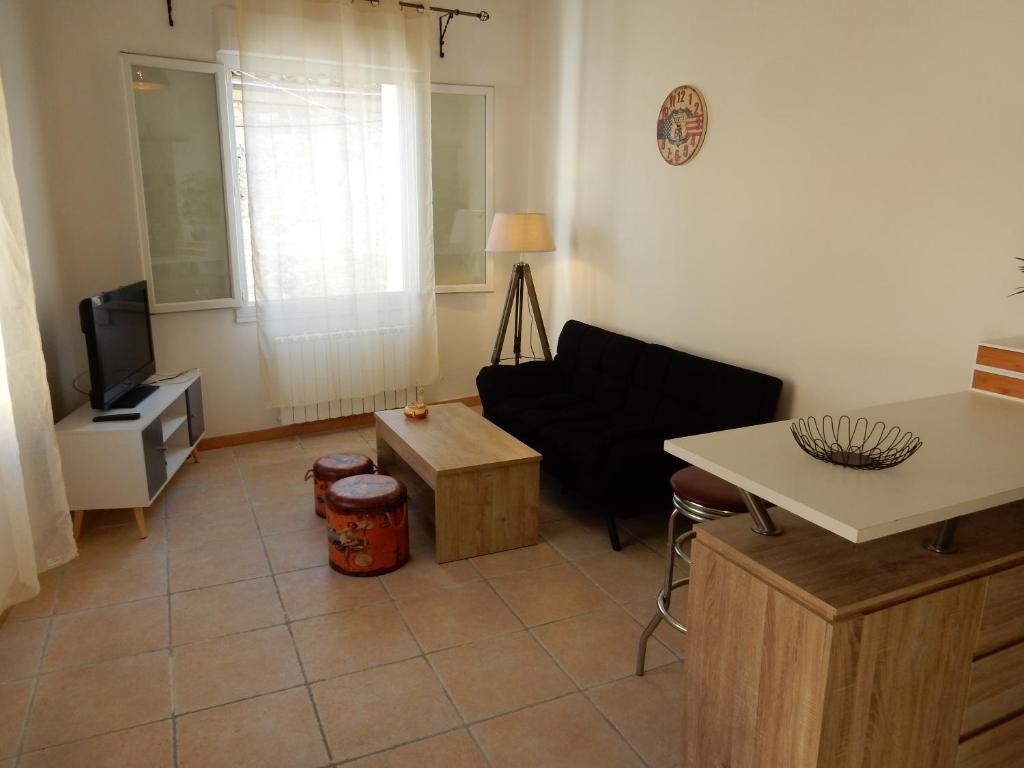 un soggiorno con divano nero e TV di SUD ET DETENTE a Gallargues-le-Montueux