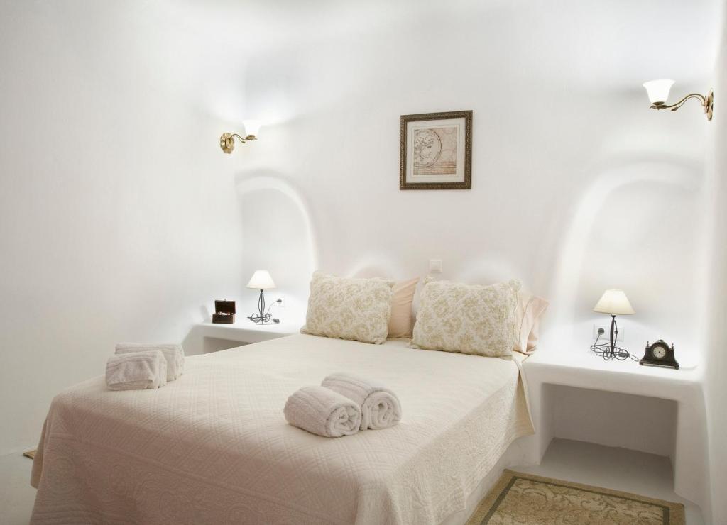 a white bedroom with a bed with towels on it at Eleni's Village Suites in Klouvas